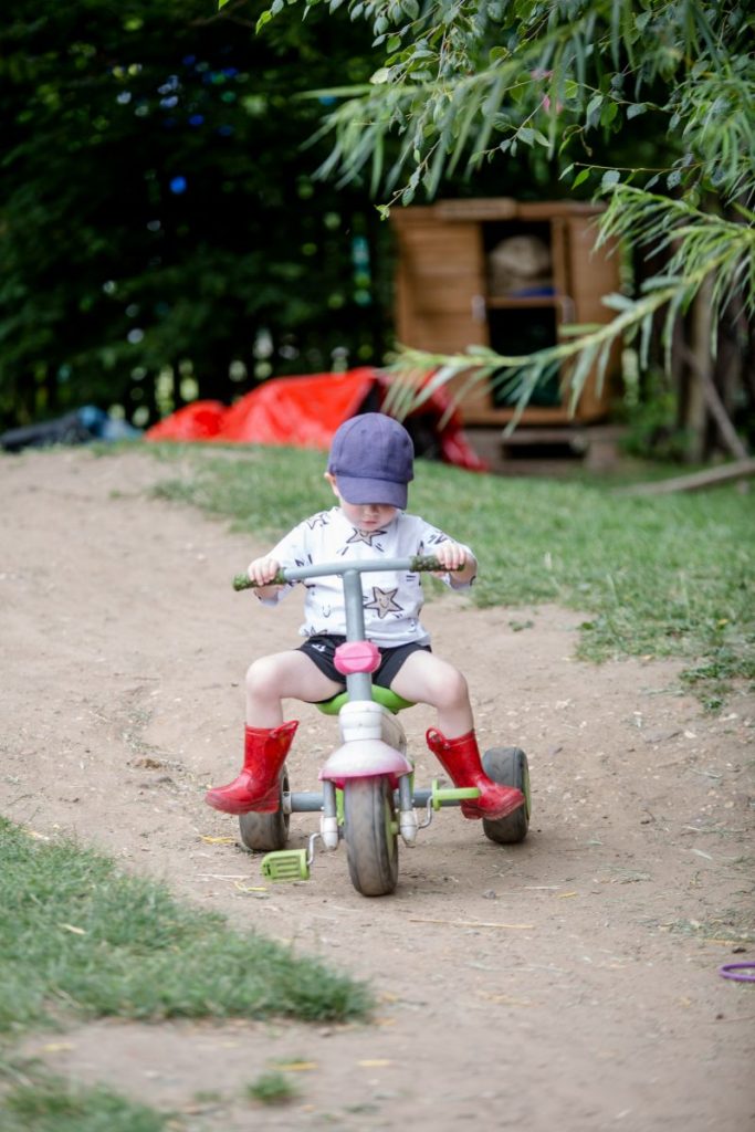 child riding a bike in the garden at blue windmill nursery